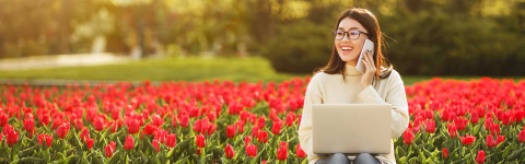 Person sitting in front of field of tulips and using devices