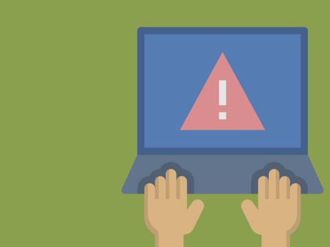 hand typing on laptop with warning icon on screen