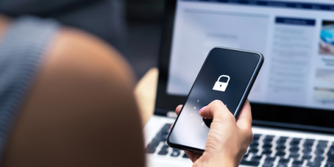 woman using her phone, on the screen of the phone is an icon of a lock.