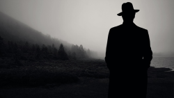 Silhouette of man wearing hat against background of mountains and forest