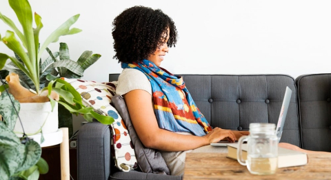 A woman using a laptop on a sofa