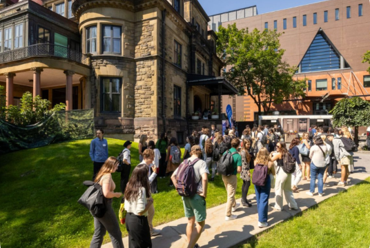 Students walking up sidewalk to enter old stone building