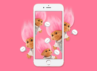 A mobile taking a photo dolls in pink background.