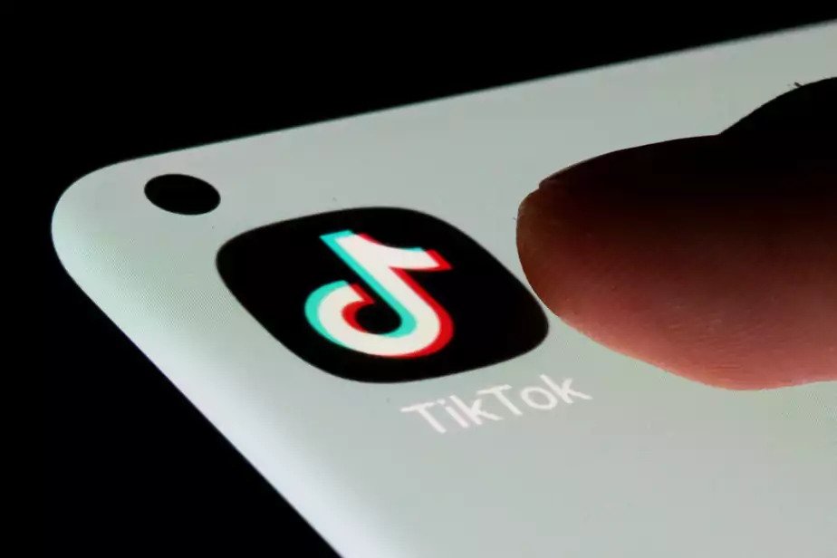 a person's finger hovers above the TikTok app on a smartphone 