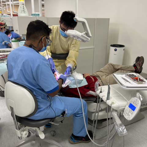 Dentists in surgical clothing working on a patient 