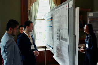 people mingling at a conference in front of a research poster