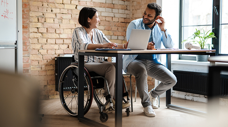 Female in wheelchair and male working at a desk with a laptop
