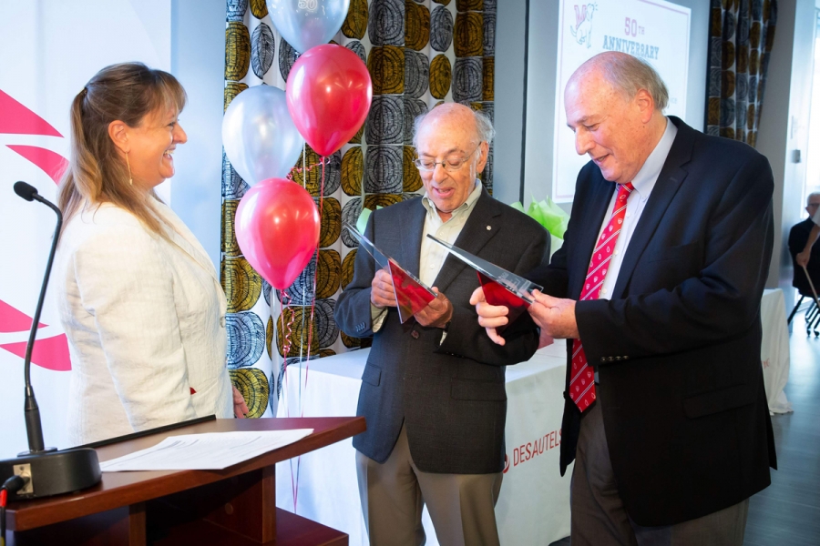 Professors Henry Mintzberg and Morty Yalovsky receiving plaques honouring their 50th anniversaries at McGill, given by Dean Isabelle Bajeux-Besnainou. 