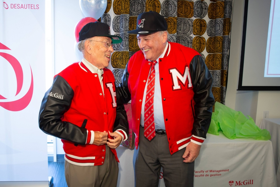 Henry Mintzberg and Morty Yalovsky try on their gifted caps and varsity jackets.