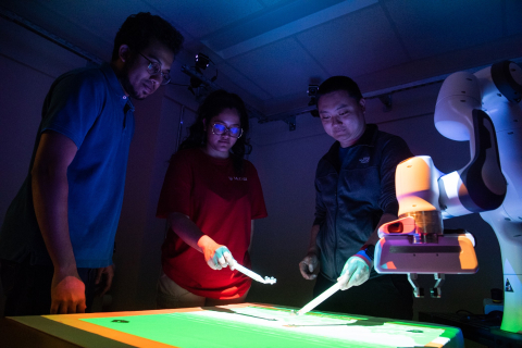 Students and a professor in an illuminated engineering lab