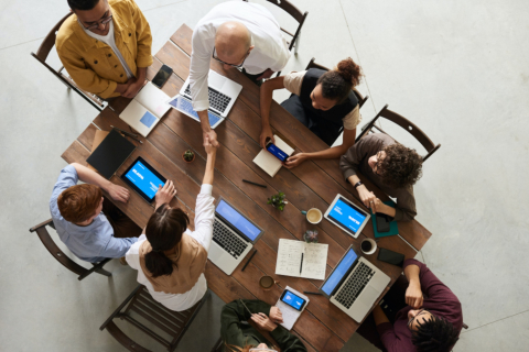 Employees shaking hands and collaborating together over a wooden table