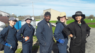 5 Agricultural Greenhouse Gases Project team members in coveralls pose outdoors between fieldwork May 2019