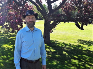 Grant Clark, Principal Investigator for the AGGP stands in front of flowering crabapple trees, 2019