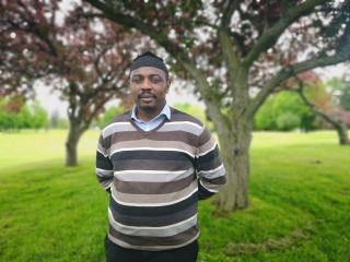 Michael Boh, research associate for the AGGP, stands in front of flowering crabapple trees, 2019