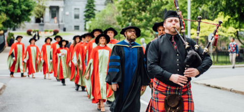 Graduates walking behind bagpiper