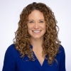 A woman with curly hair in a blue dress.