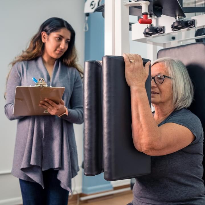 Kinesiology student oversees a senior woman's workout 
