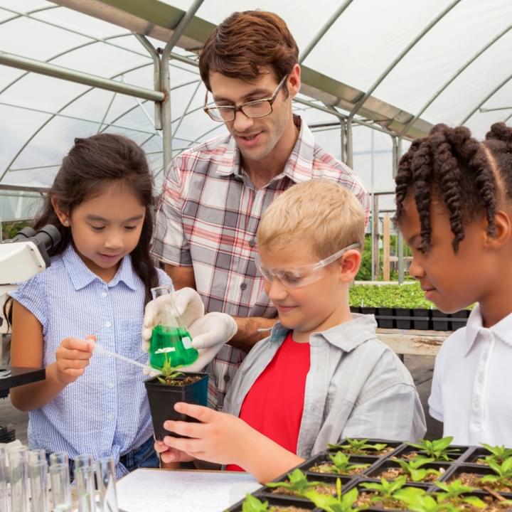 Teacher in a greenhouse with elementary school students