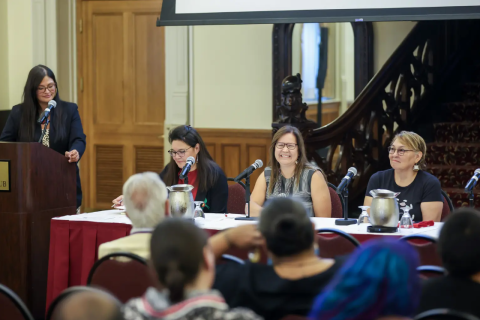 OFNIE partners seated at a table next to a podium at the Faculty Club.