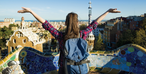 Female student with backpack on a cliff somewhere foreign, examining the view