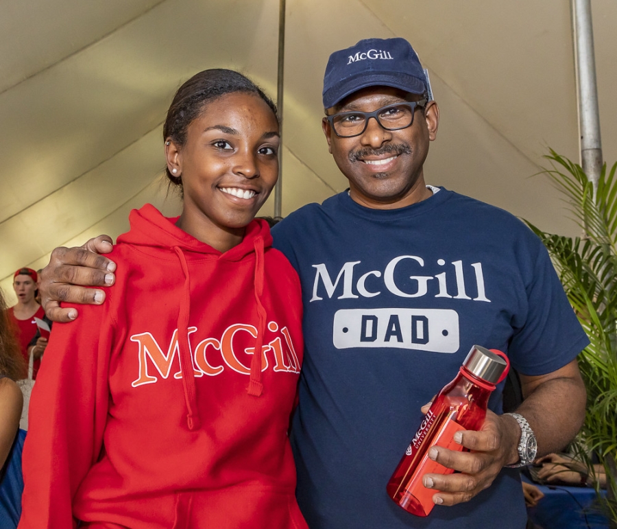 Dad and Daughter at Parents&#039; Tent. Black family wear McGill shirts and smile at the camera.