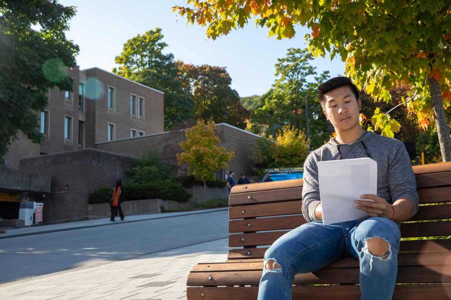 Student sitting in front of the Faculty of Education Building