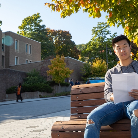 Student sitting in front of the Faculty of Education Building