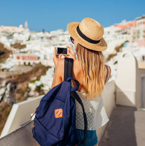 Blonde female student photographs Santorini views