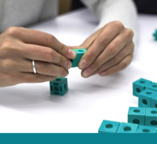 Hands holding together small cube building blocks