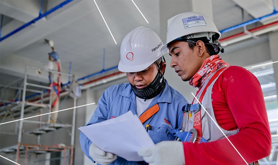 Two engineers reviewing their plans in a brightly lit factory