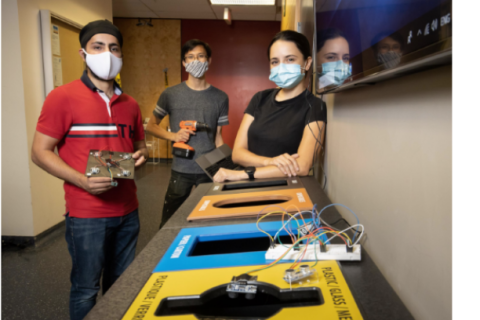 Three students holding electrical and mechanical apparatus