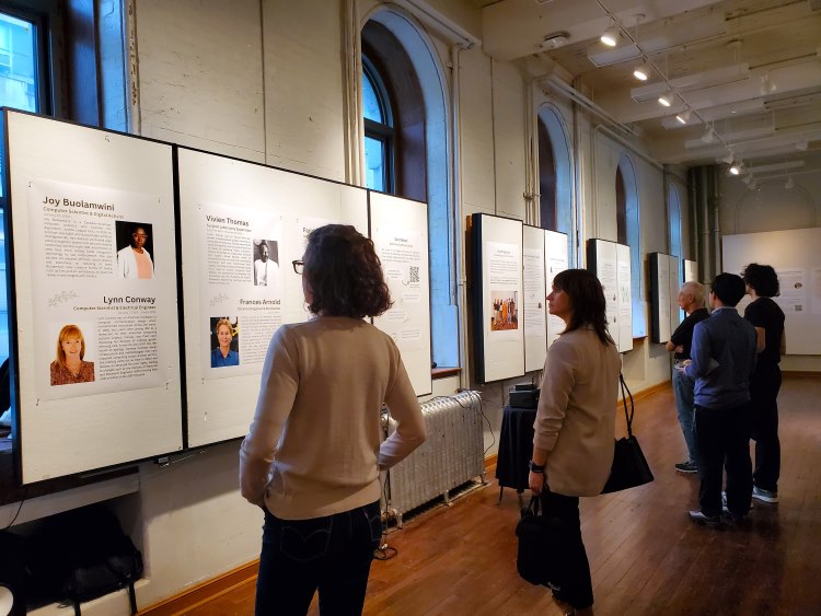 Guests looking at the intern projects on the wall at the 2024 E-IDEA student showcase event
