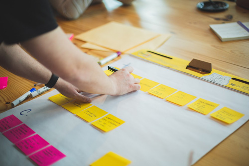 a person writing on sticky notes and organizing them on a note pad