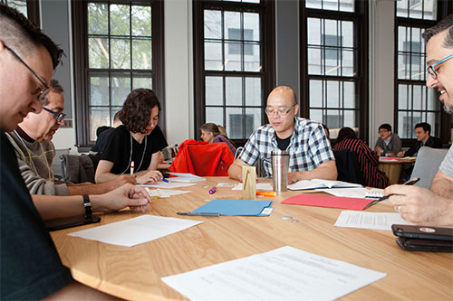 a group of people siting at a conference table and writing on papers