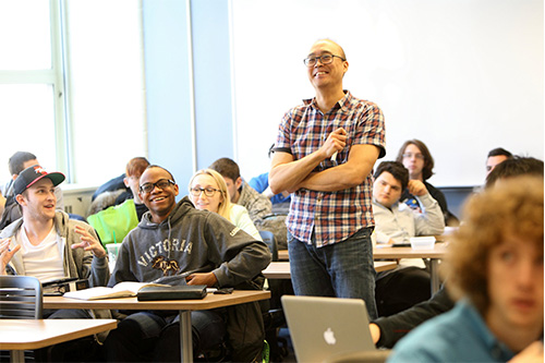 Professor listening to a student speak in the middle of a classroom