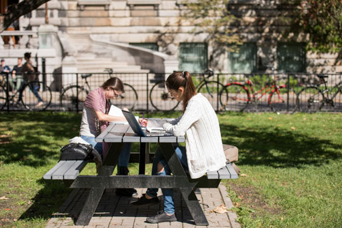 2 students studying on a bench outside the McDonald Engineering building