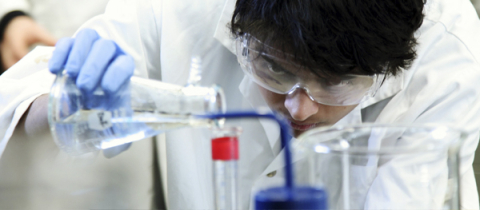 A student pouring liquid to a beaker