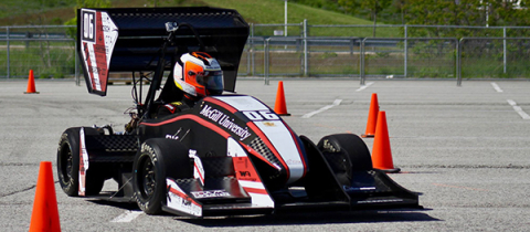 A racing car being driven between small cones