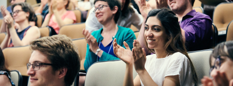 Student sitting in an auditorium and clapping