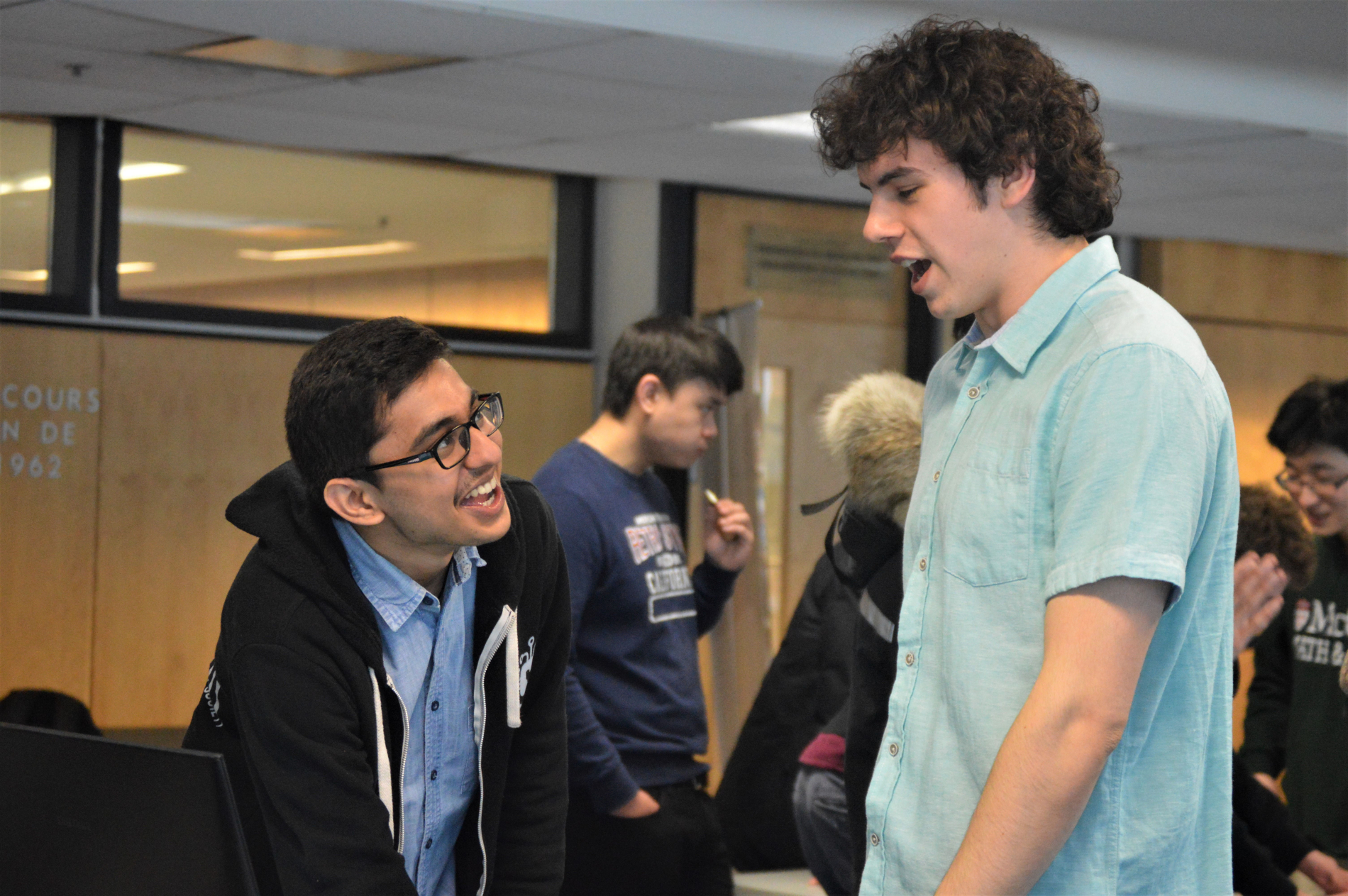 2 students discussing, with groups talking in the background