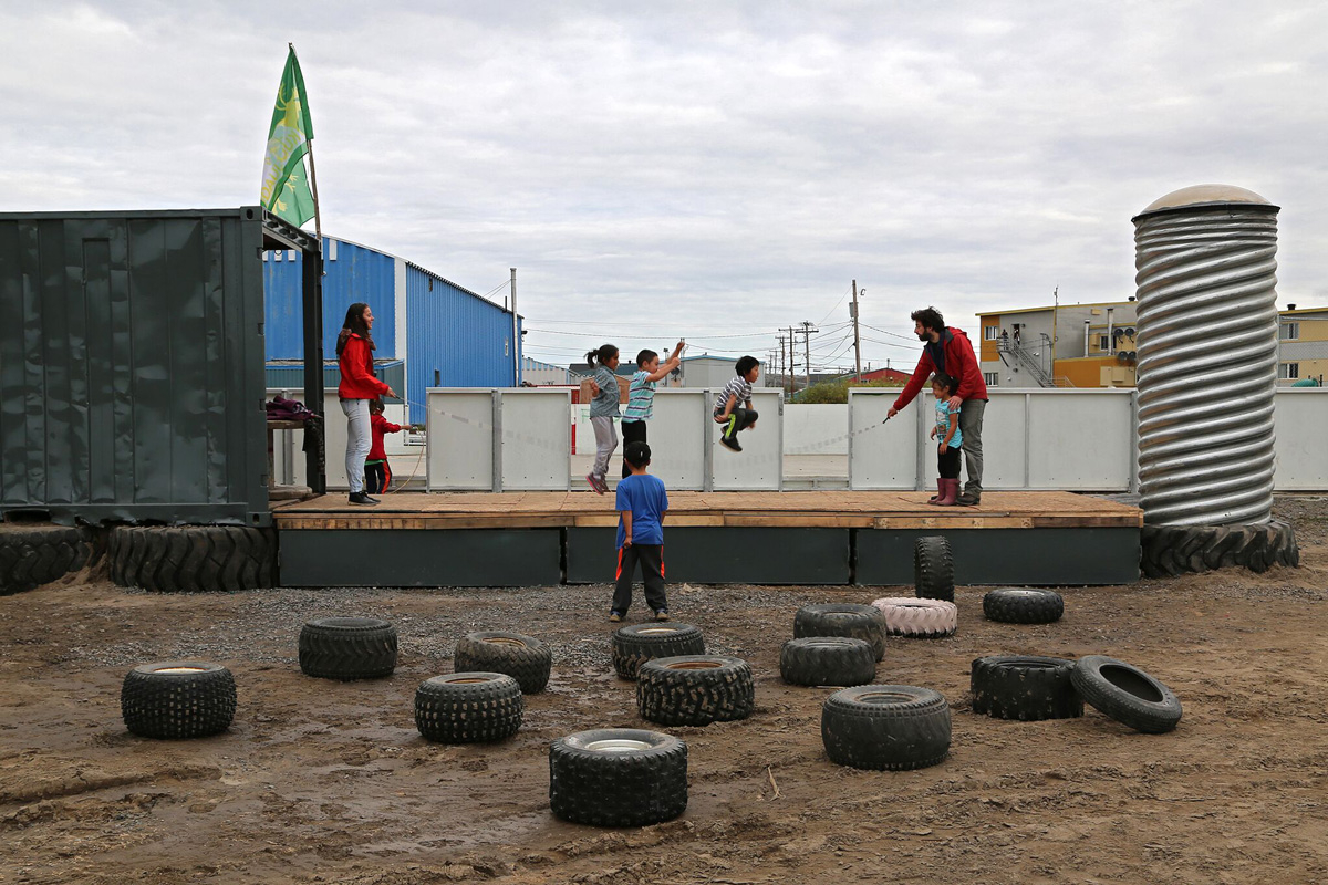 Children playing on land that has been rejuvenated using recycled materials; tires scattered on ground