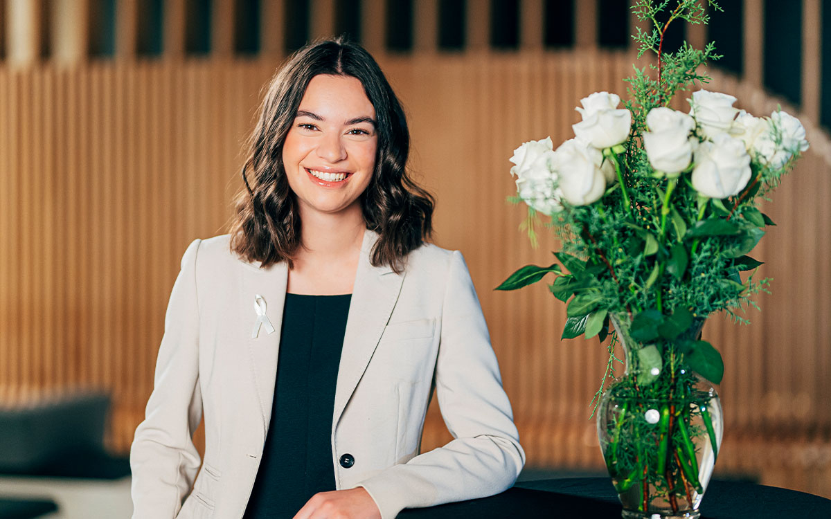 Sophia Roy standing next to a vase filled with white roses