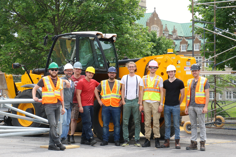 Group of workers posing in front of a construction vehicle