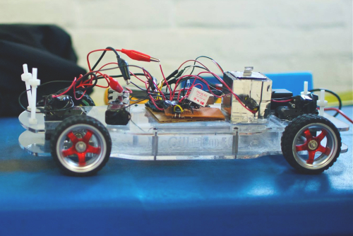 Base of  a small car with wheels and electrical circuit boards and wires on top of it