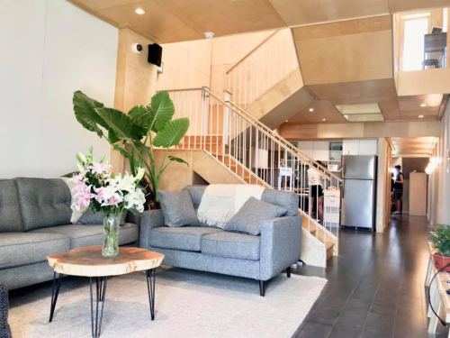 A furnished lounge, stairs and a kitchen inside Deep Performance Dwelling 