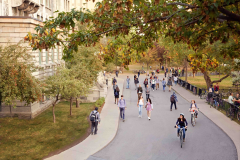 People walking along a promenade under autumn foliage