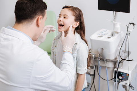 Physician examines throat of young girl