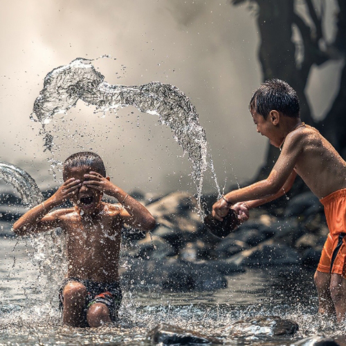 Children in a street splashing and playing in clean water