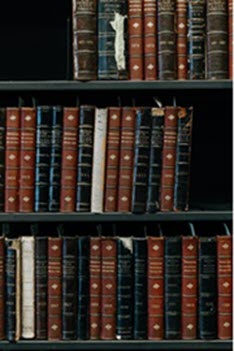 three selves of old brown, black and white covered leather books