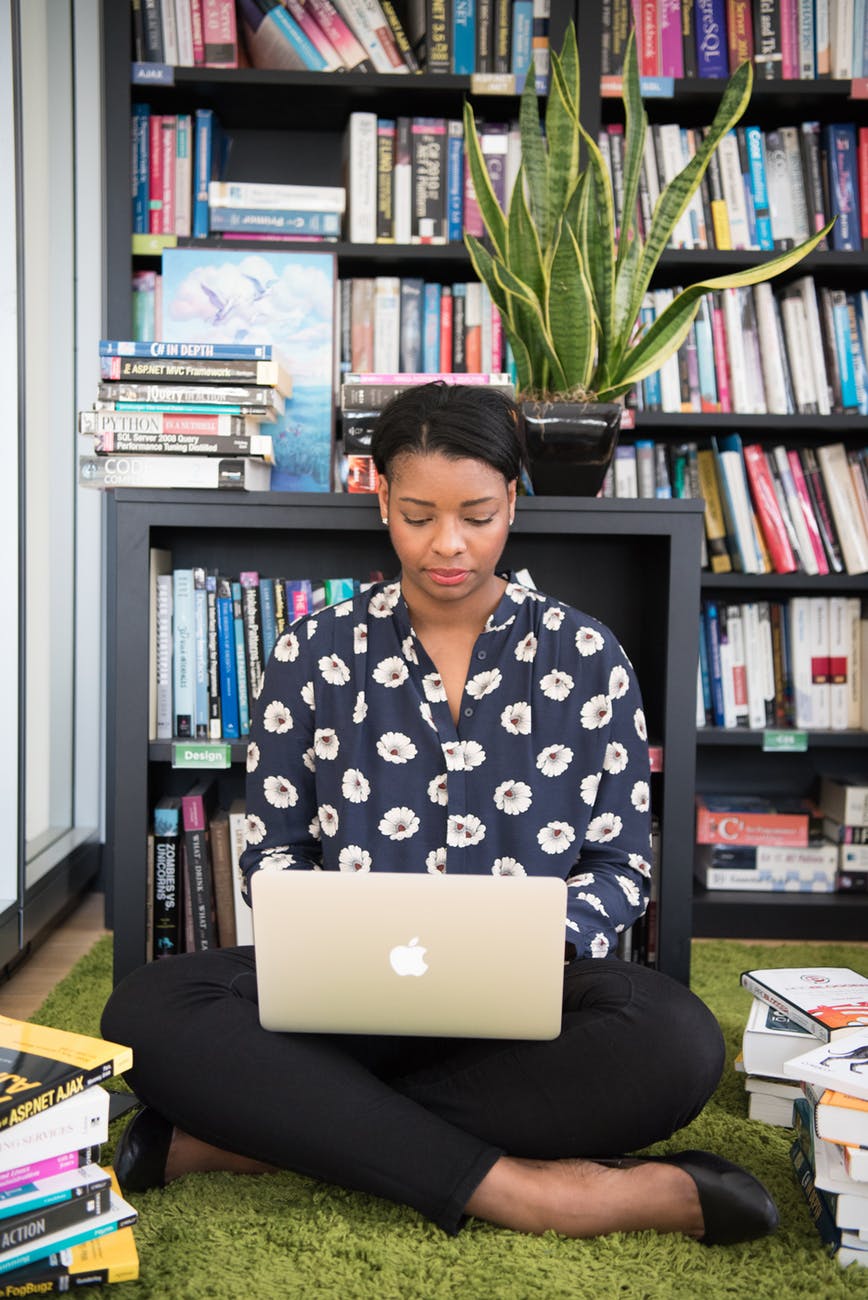 Woman writing on computer sitting in front of a bookshelf